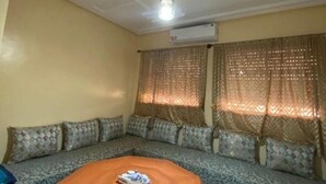 A room with a sofa set against a wall, an air conditioning unit, and a ceiling light fixture. - Furnished apartment with 2 bedrooms, kitchen, bathroom and living room (Meknès)