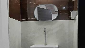 Un baño con un lavamanos blanco, un espejo y una lámpara.