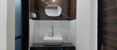 A bathroom with a white sink, a mirror, and a marble backsplash.