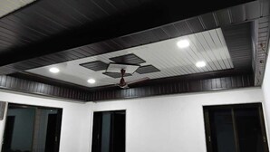 A room with a dark wooden ceiling, recessed lighting, and a ceiling fan. - Hotel Jijau Darbar (Mahād)