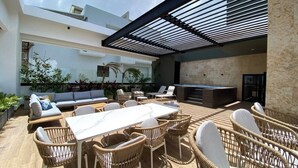 An outdoor patio with a dining area, lounge chairs, and a bar. - Modern Santo Domingo Apartment in Exclusive Naco Sector (Santo Domingo)