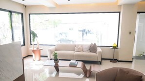 A modern living room with a beige sofa, a coffee table, and a brown armchair. - Modern Santo Domingo Apartment in Exclusive Naco Sector (Santo Domingo)
