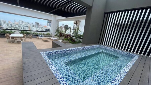 A rooftop pool with a tiled edge, surrounded by a wooden deck and outdoor furniture. - Modern Santo Domingo Apartment in Exclusive Naco Sector (Santo Domingo)
