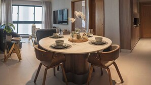 A modern dining area with a round table, six chairs, and a centerpiece of white flowers. - Modern Santo Domingo Apartment in Exclusive Naco Sector (Santo Domingo)