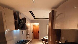 A modern kitchen with wooden cabinets, a built-in stove, and a dining area with a round table and chairs. - Modern Santo Domingo Apartment in Exclusive Naco Sector (Santo Domingo)
