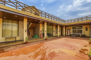 Un patio amplio con un área de estar techada, una escalera y un ventanal grande.