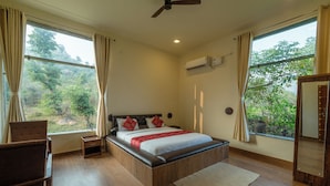 A bedroom with a wooden bed, a nightstand, a chair, and a large window with curtains.