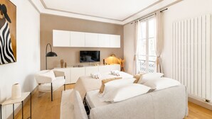 Une chambre d’hôtel moderne équipée d’un canapé, d’une télévision, d’un bureau et d’une grande fenêtre.