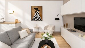 Un salon moderne avec un canapé, une table basse, un téléviseur et un tableau accroché au mur.