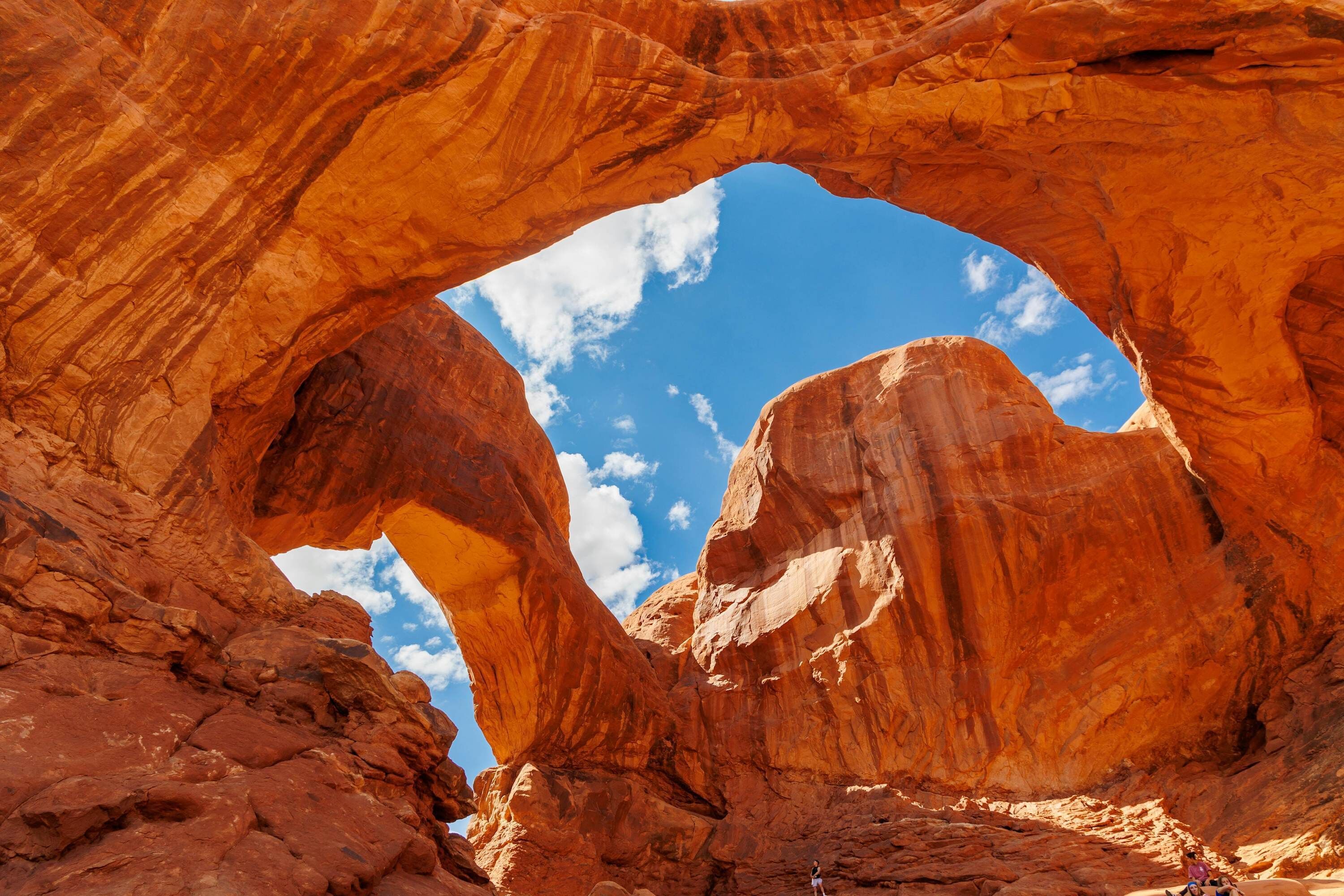 A natural rock arch formation with a clear blue sky visible through the opening.