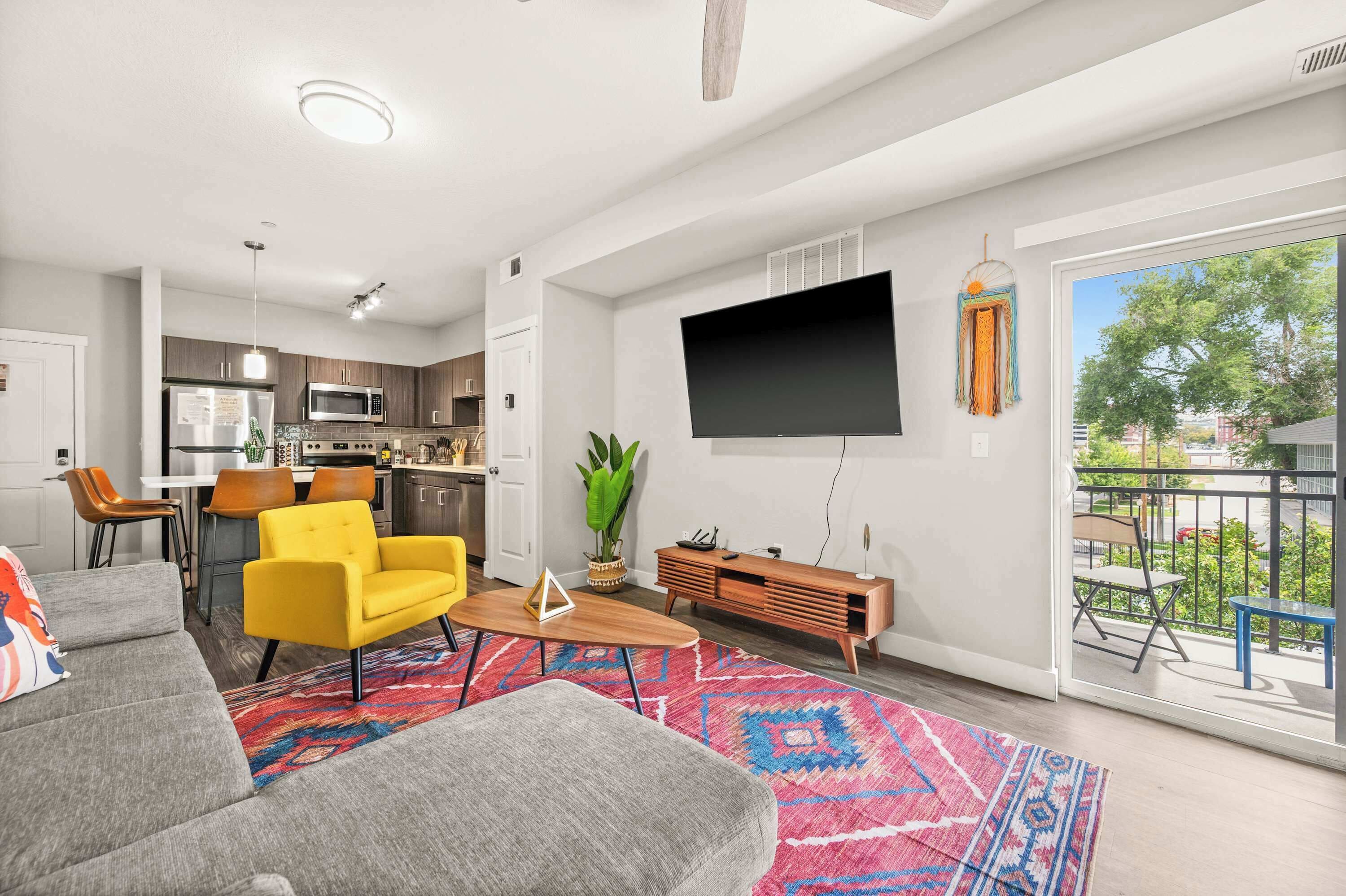 A modern living room with a sofa, yellow armchair, and a TV on the wall.