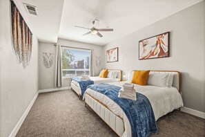 Ein Schlafzimmer mit zwei Betten, einem Deckenventilator und Bildern an den Wänden.