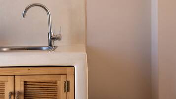 Un baño con un mueble de madera, un lavabo blanco con un grifo moderno y una cesta de mimbre con toallas.