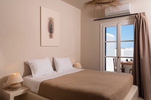 Quarto com cama, luminárias de cabeceira, janela com cortinas e ar-condicionado fixado na parede.