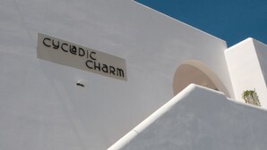 A building with a sign reading "Cycadic Charm" and a clear blue sky. - Cycladic Charm (Naousa)