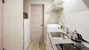 A compact kitchen with a refrigerator, microwave, sink, kettle, and a small countertop. - Viento Ikebukuro (Tokyo)