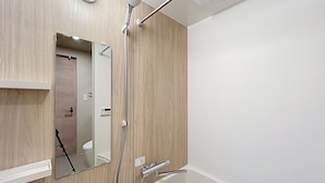 A modern bathroom with a wooden vanity, a mirror, a shower with a handheld showerhead, and a bathtub. - Viento Ikebukuro (Tokyo)