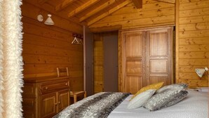 A wooden cabin bedroom with a bed, a dresser, and a wardrobe. - Chalet on the edge of town, close to the Balme cable car (La Clusaz)