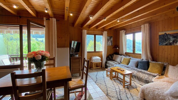 A wooden cabin interior with a dining area, sofa, and TV. - Chalet on the edge of town, close to the Balme cable car (La Clusaz)