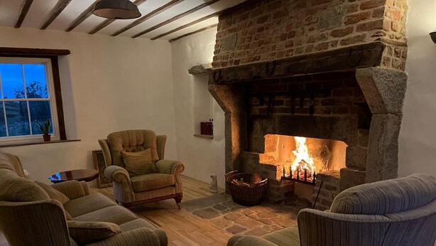 Un salón acogedor con chimenea de piedra, vigas de madera y asientos cómodos.