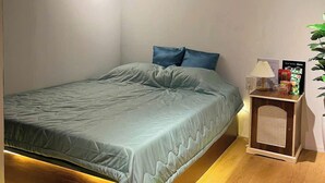 A bedroom with a bed, a bedside table, a lamp, and an air conditioning unit. - MMT Homestay (Can Tho)