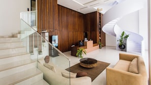 Un hall d’entrée moderne avec un escalier en verre, des lambris en bois, un comptoir d’accueil et un escalier en colimaçon.