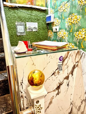 A marble counter with a decorative globe, a QR code, and a phone charging station. - Hotel S Elite - near Temple & Station (Ujjain)