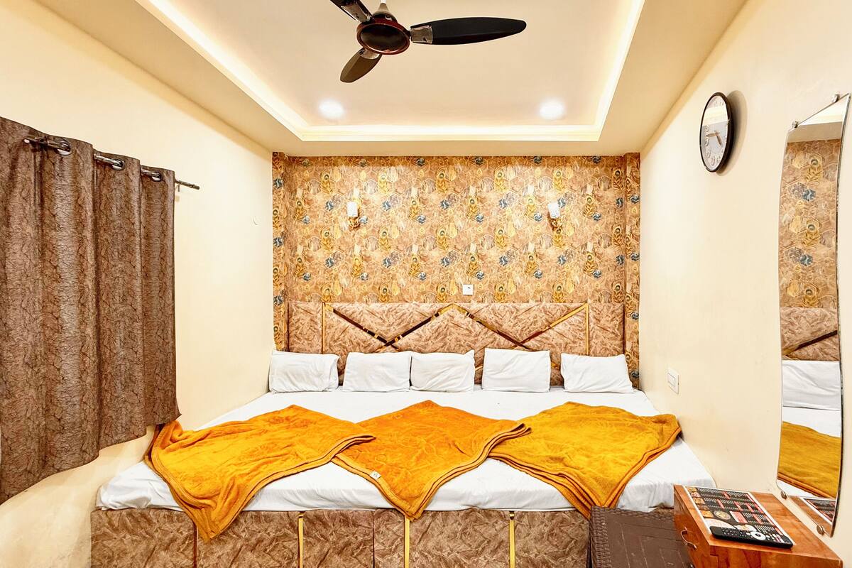 A bedroom with a bed, curtains, a ceiling fan, a wall clock, and a mirror.
