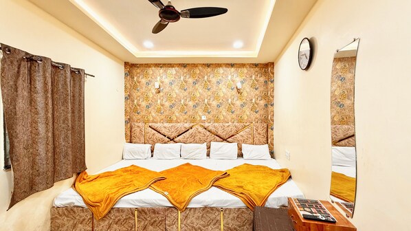 A bedroom with a bed, curtains, a ceiling fan, a wall clock, and a mirror. - Hotel S Elite - near Temple & Station (Ujjain)