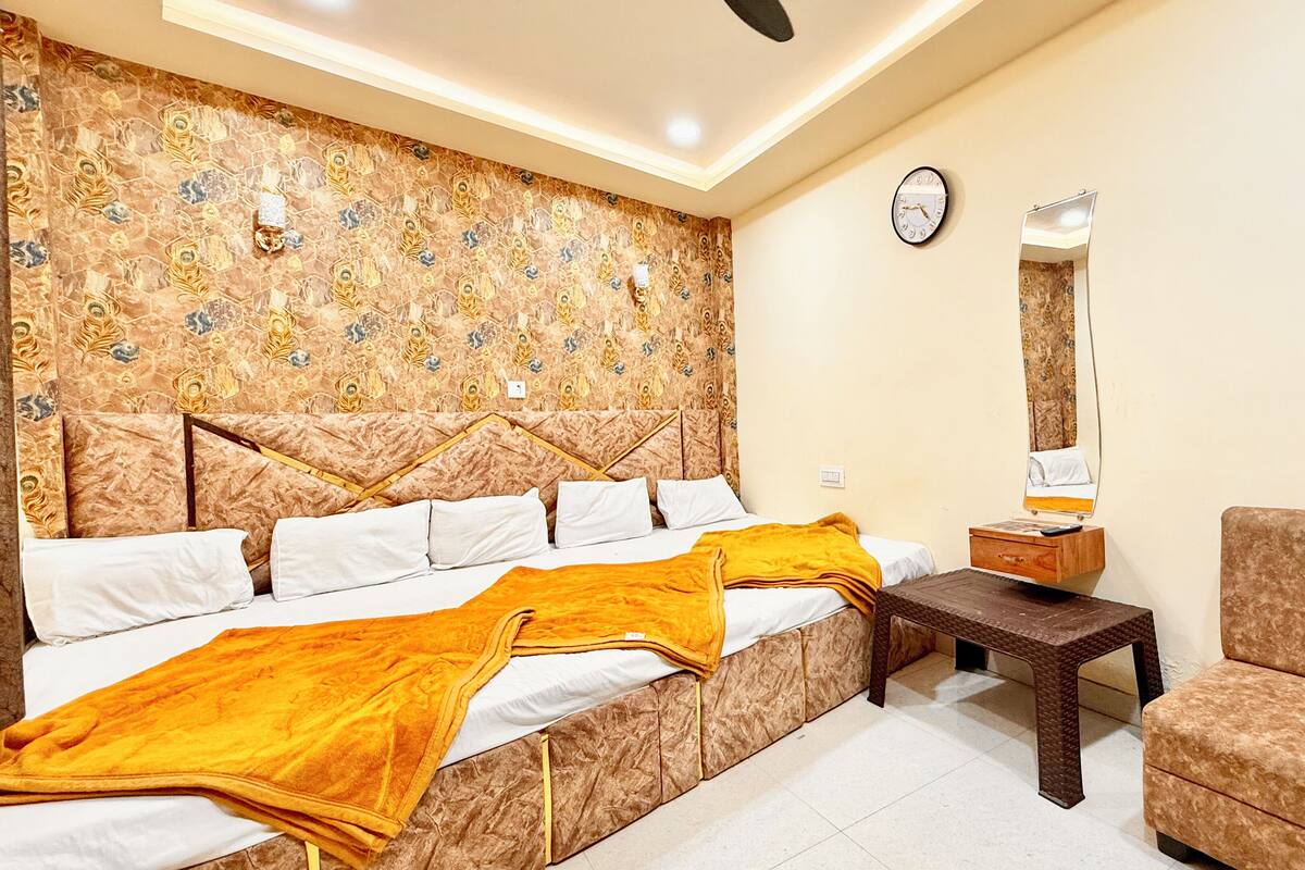 A hotel room with a bed, a nightstand, a mirror, a chair, and a patterned wall.