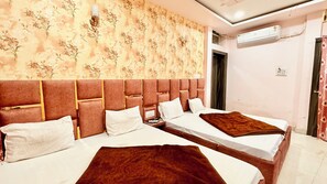 A hotel room with two beds, a large floral-patterned wall, a brown headboard, and an air conditioning unit. - Hotel S Elite - near Temple & Station (Ujjain)