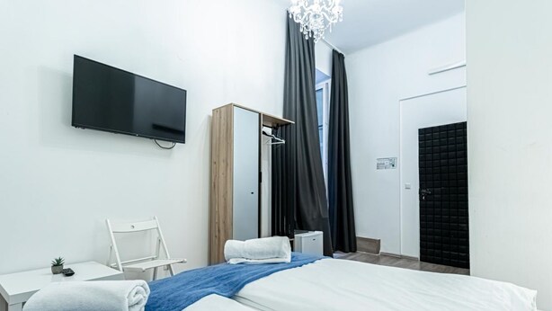 Une chambre d’hôtel moderne équipée d’un lit, d’un bureau, d’une chaise, d’une télévision et d’une armoire.