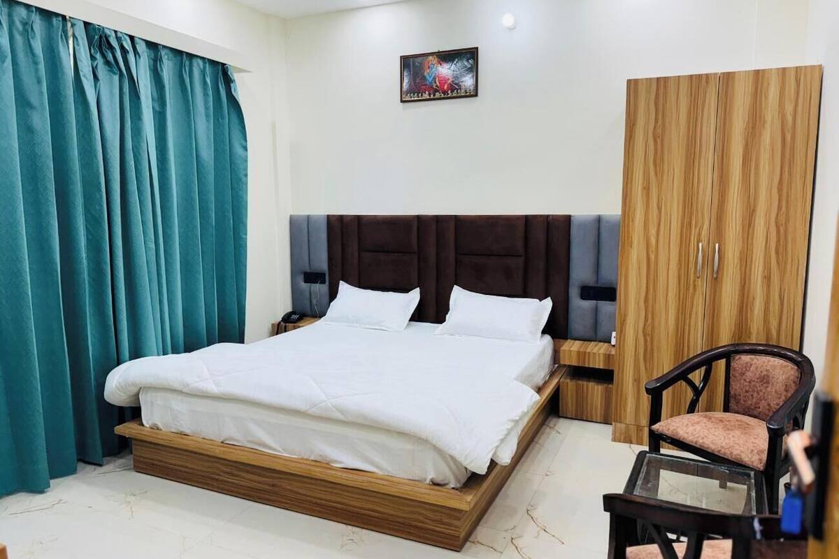 Um quarto com uma cama grande, um guarda-roupa de madeira, uma cadeira e um quadro na parede.
