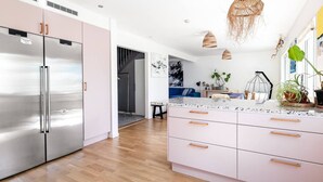 Una cocina moderna con electrodomésticos de acero inoxidable, encimera rosa y suelo de madera.