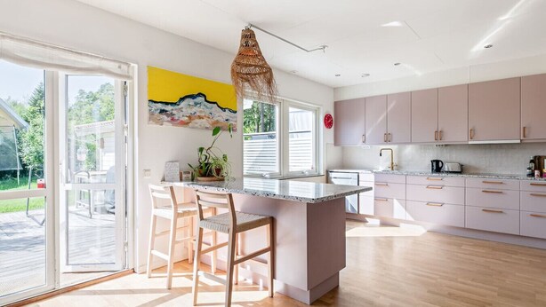 Una cocina moderna con una isla grande, puertas de vidrio correderas y vistas al exterior.