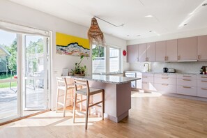 A modern kitchen with a large island, sliding glass doors, and a view of the outdoors. - Spacious Family Home with Backyard (Stockholms län)