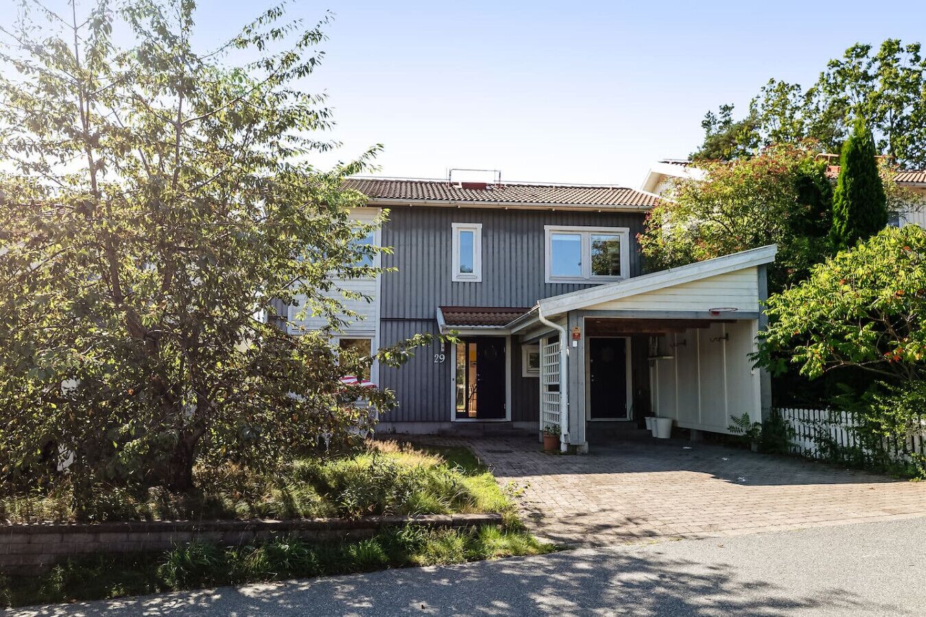 Een huis met twee verdiepingen, een overdekte veranda, een garage en een nummer 29.