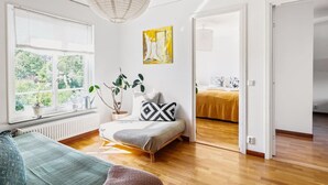 Una habitación luminosa con una cama, una ventana, un radiador y una planta.
