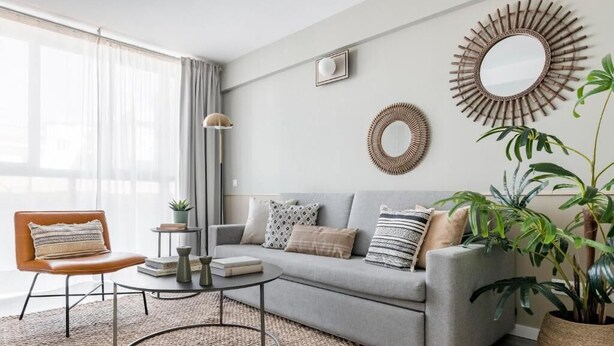 A modern living room with a grey sofa, a round coffee table, a brown leather chair, and two large mirrors on the wall. - Cool Apartments by Olala Homes (Madrid)