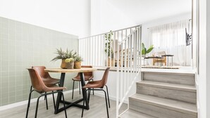 A modern kitchen with a dining area, featuring a wooden table, brown chairs, and a staircase leading to an upper level. - Cool Apartments by Olala Homes (Madrid)