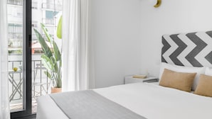 A modern hotel room with a large bed, a small bedside table, a potted plant, and a view of the outside balcony. - Cool Apartments by Olala Homes (Madrid)