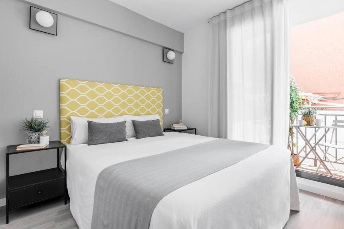 Un dormitorio moderno con una cama grande, una mesita de noche y vistas al balcón.