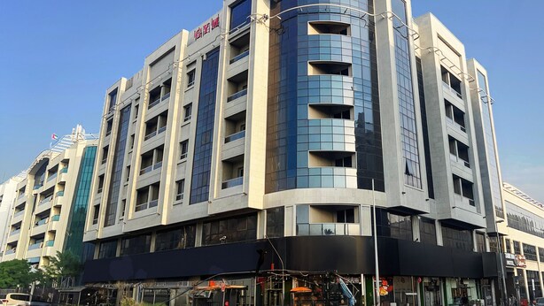 A modern hotel with a curved facade, multiple balconies, and a prominent signage at the top. - Tamr Inn Hotel (Dubai)