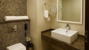 A modern bathroom with a toilet, bidet, sink, and mirror. - Tamr Inn Hotel (Dubai)