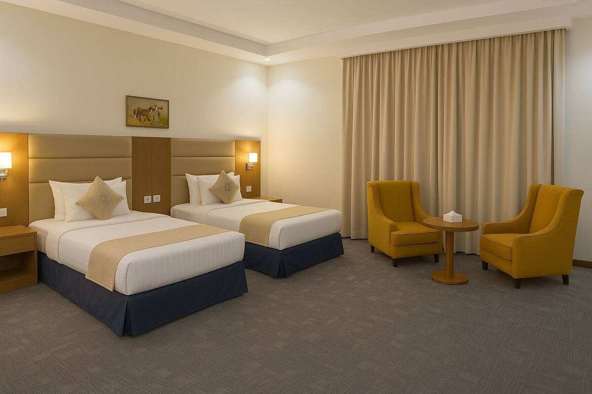 A hotel room with two beds, a small table, two chairs, and a large window with curtains.
