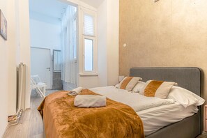 Un dormitorio con una cama, una ventana y una puerta que da a un baño.