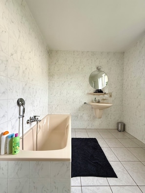 A bathroom with a bathtub, a sink, and a mirror. There are toiletries on the edge of the tub. - Zen House Clervaux Castle at 10 min (Clervaux)
