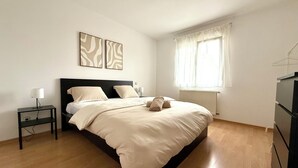 A bedroom with a bed, bedside tables, a radiator, and a window with curtains. - Zen House Clervaux Castle at 10 min (Clervaux)