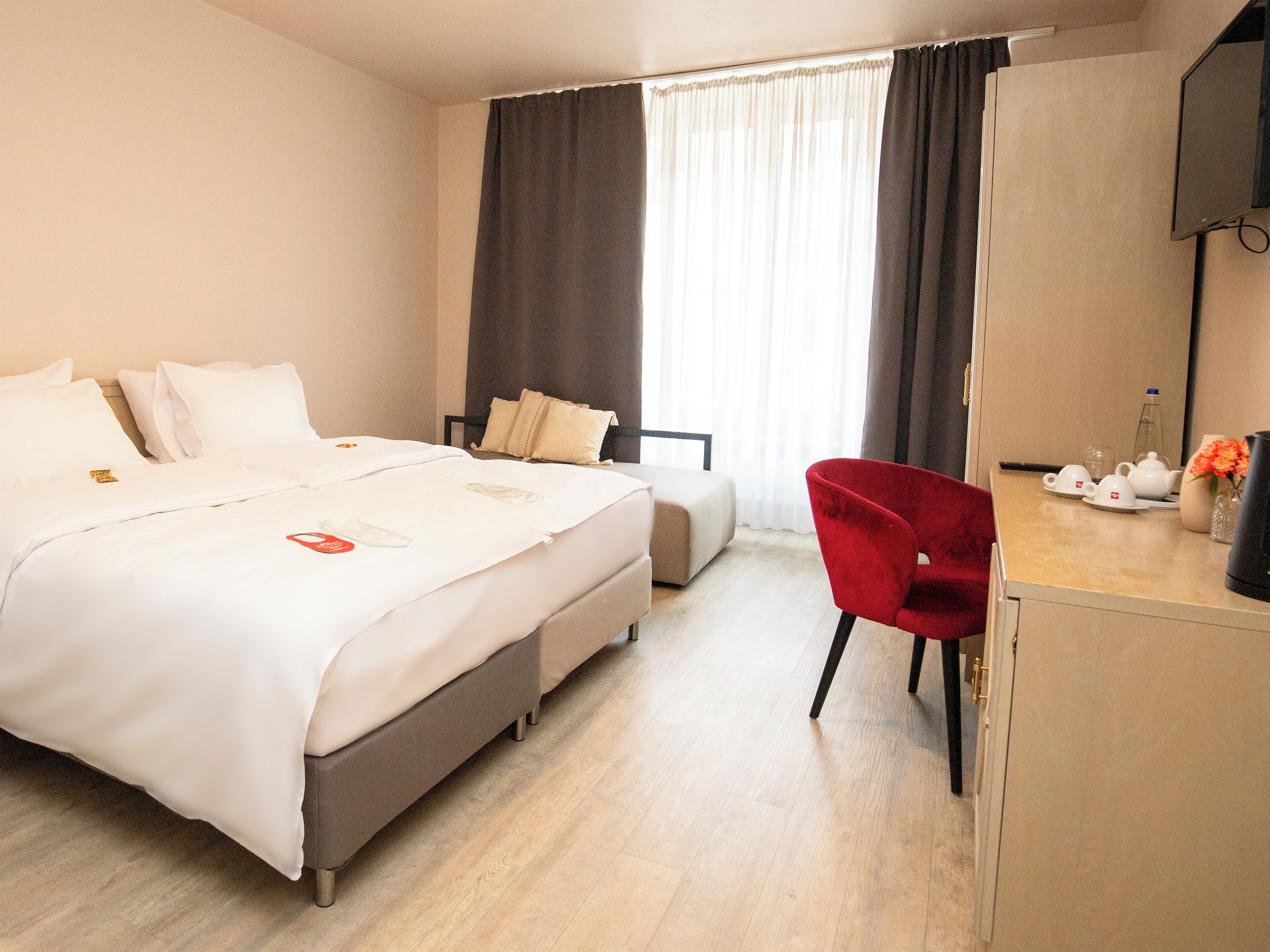 A hotel room with a bed, a desk, a chair, and a TV.