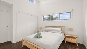 A bedroom with a bed, two bedside tables, a window, and a door. - The Palm House in Cowes (Cowes)